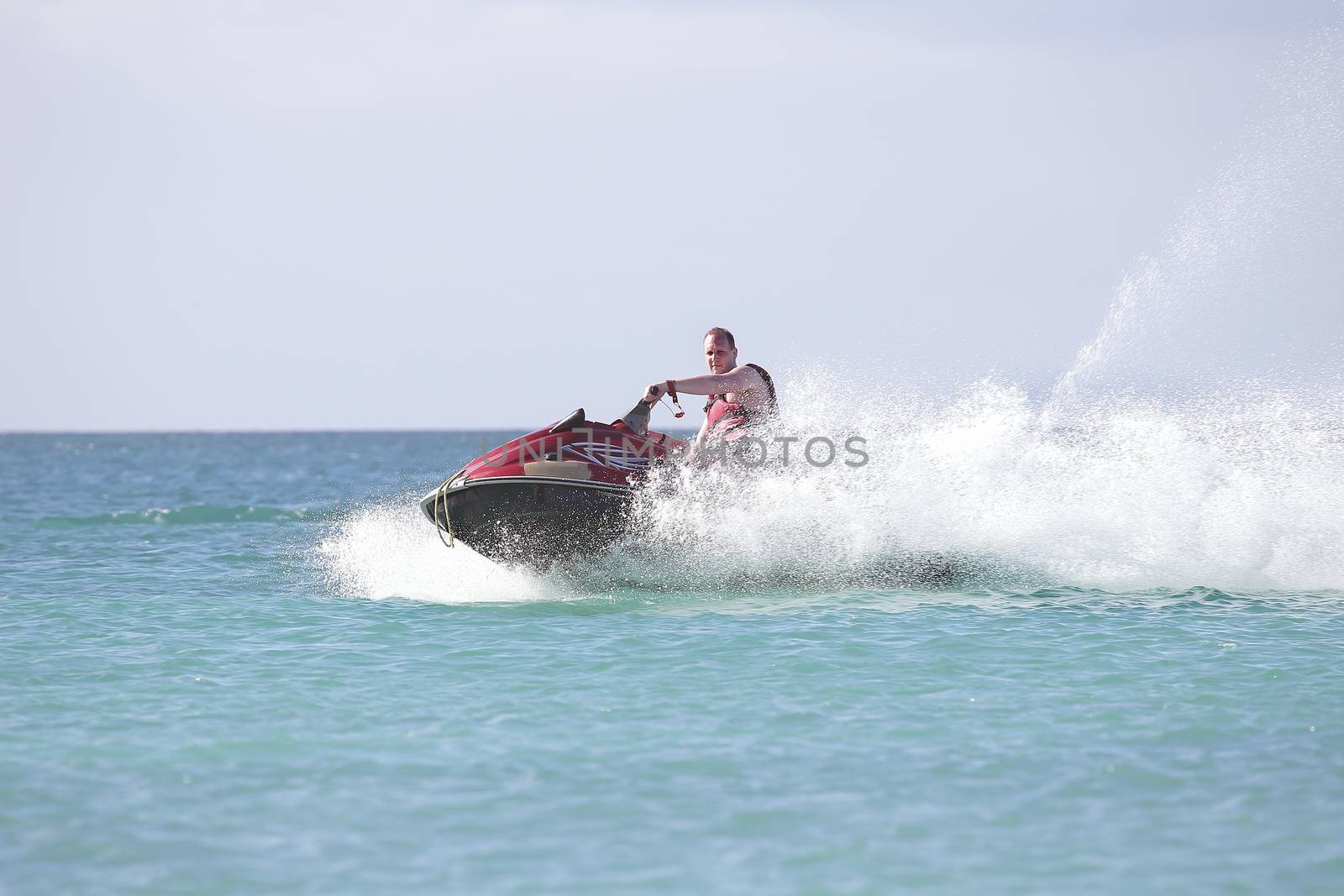 Young guy cruising on the caribbean sea on a jet ski