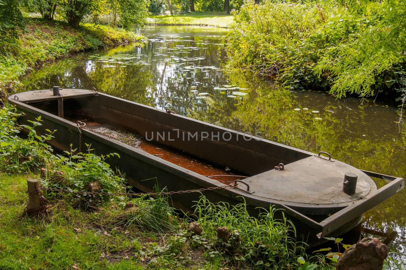 Old rusty boat by riverbank in park