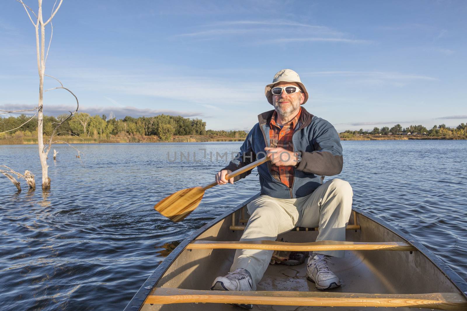 senior male enjoying morning sun on lake in a canoe, Riverbend Ponds Natural Area, Fort Collins, Colorado