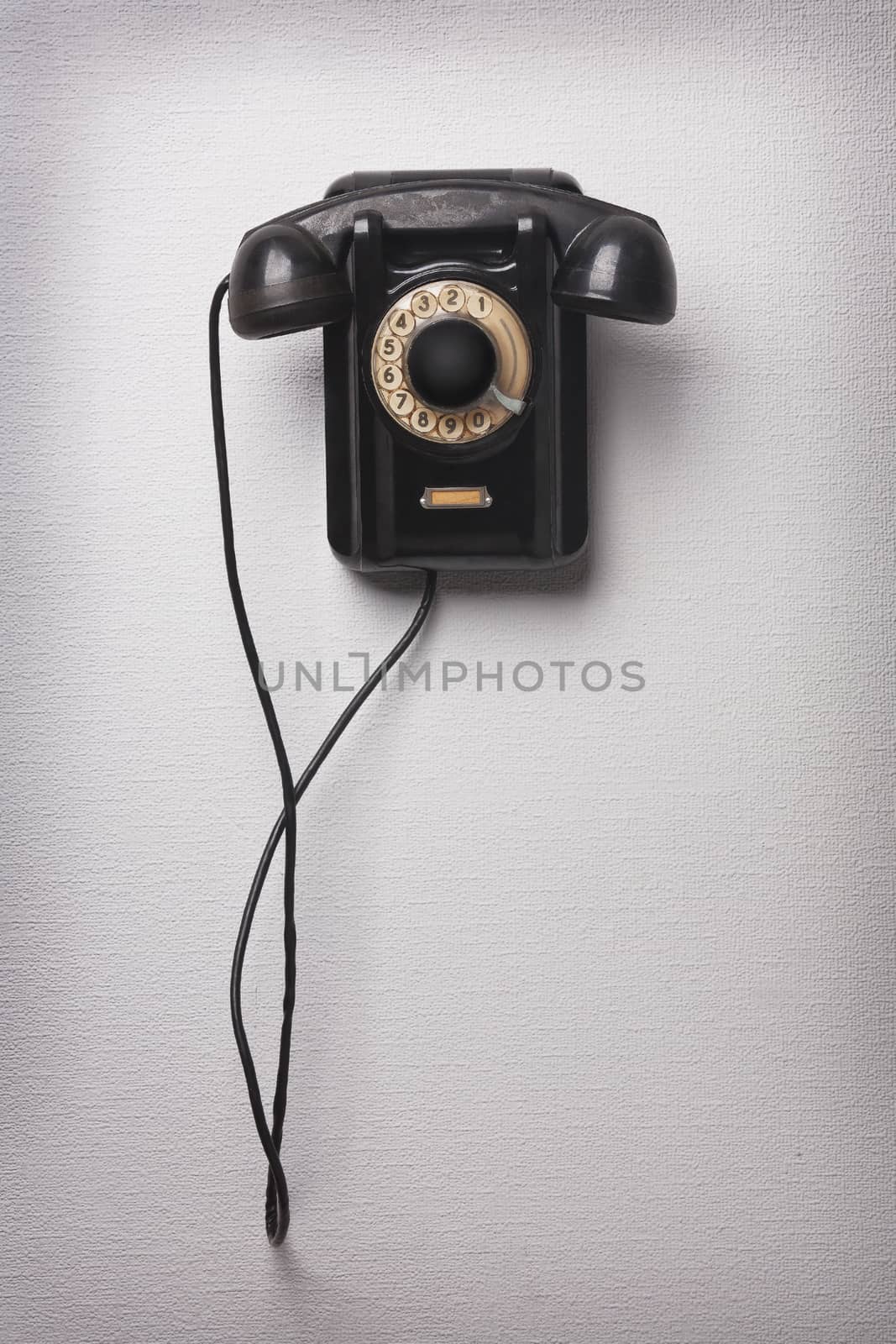 Old black rotational phone on wall