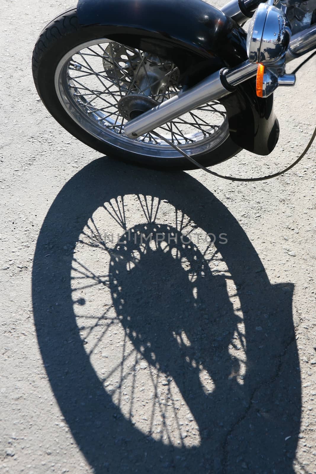 Front wheel of motorcycle and shade on asphalt