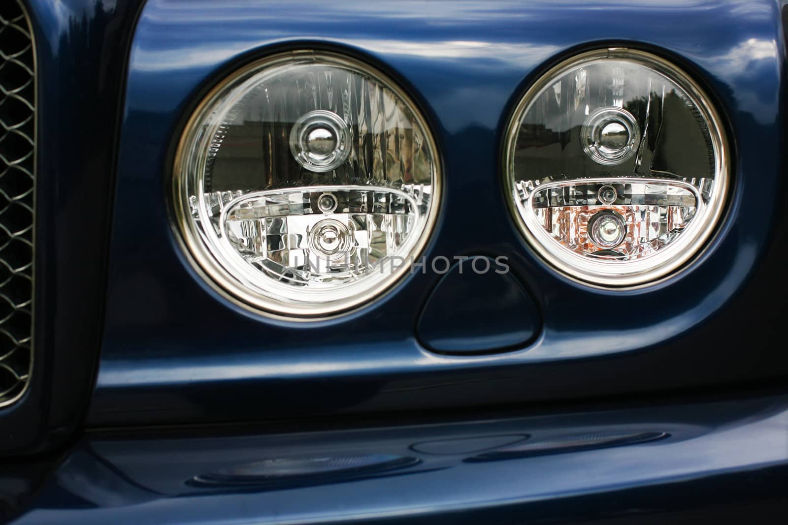 Forward part of the case of the prestigious car of dark blue colour with headlights.