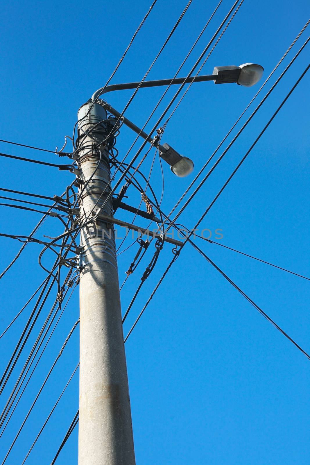 Column with lanterns electric wires against sky 