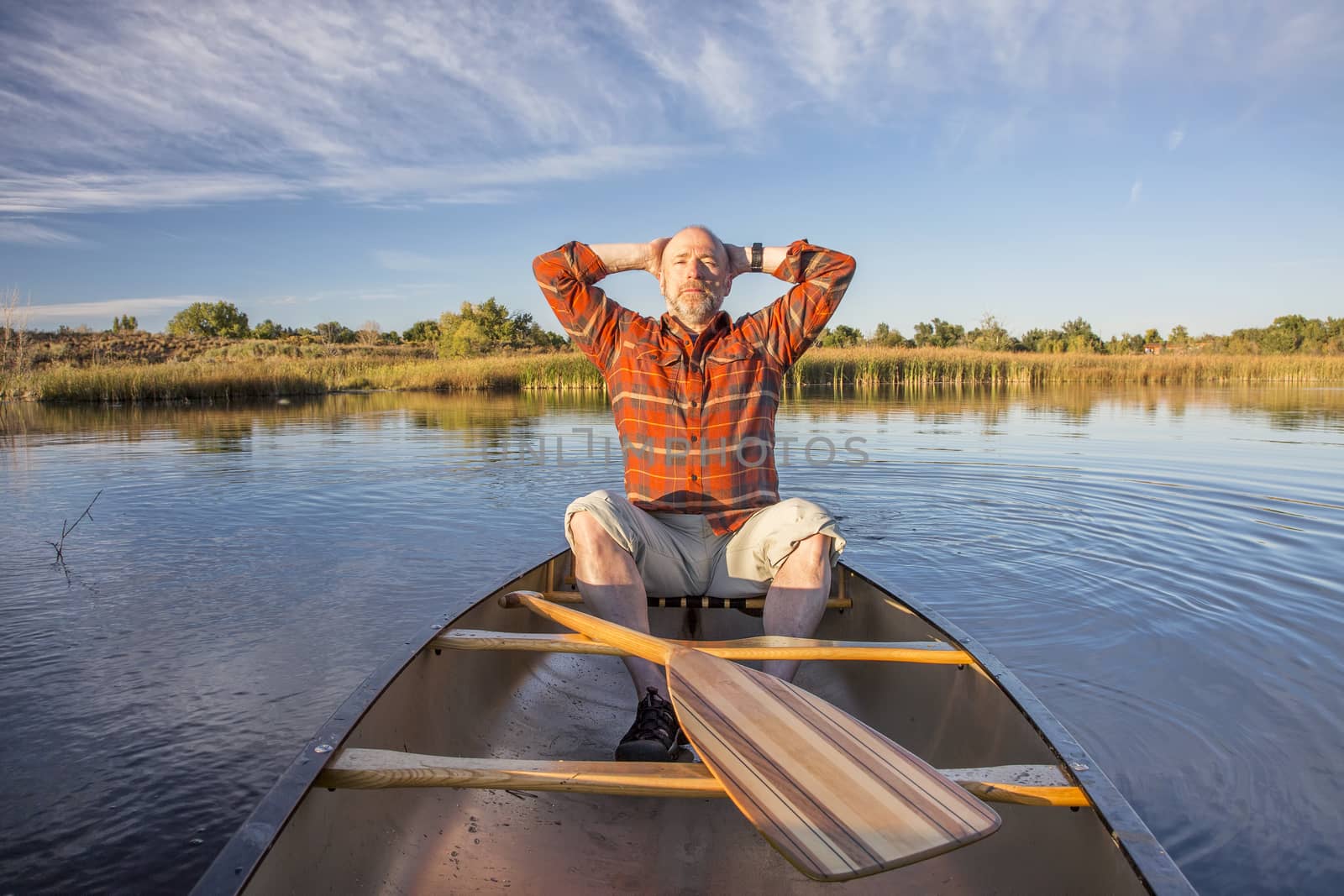 senior male enjoying evening sun on lake in a canoe, Riverbend Ponds Natural Area, Fort Collins, Colorado