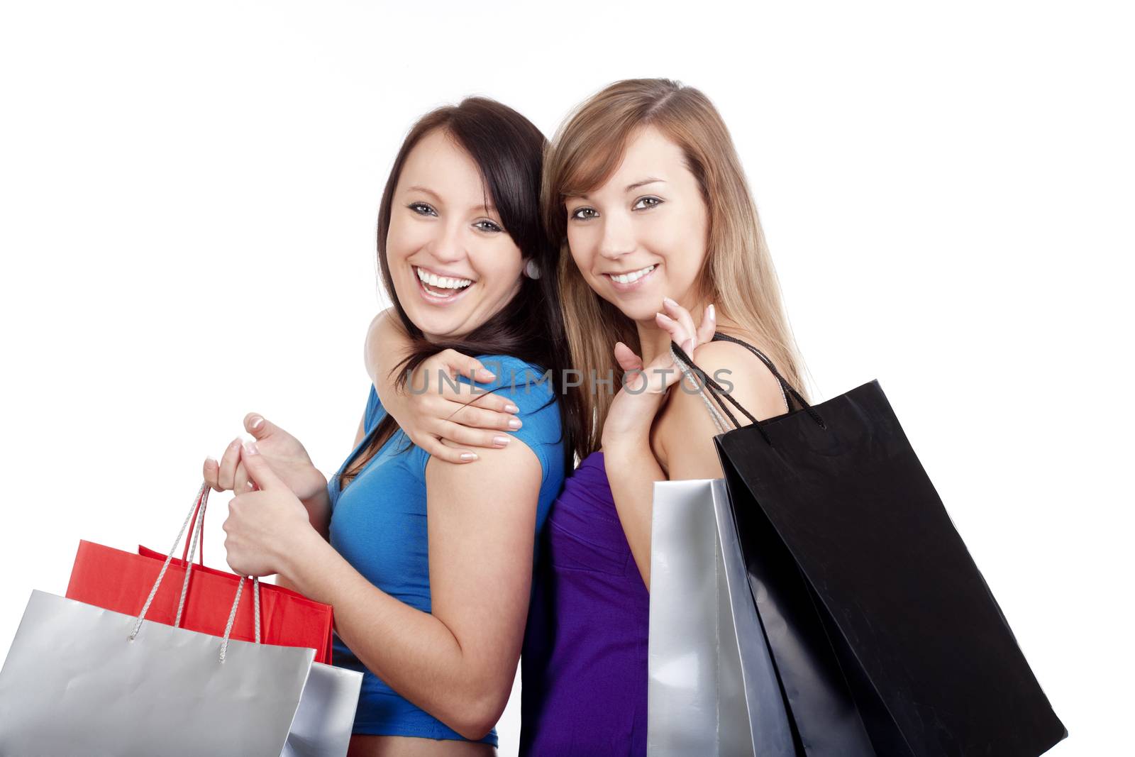 two happy young girls with shopping bags smiling - isolated on white