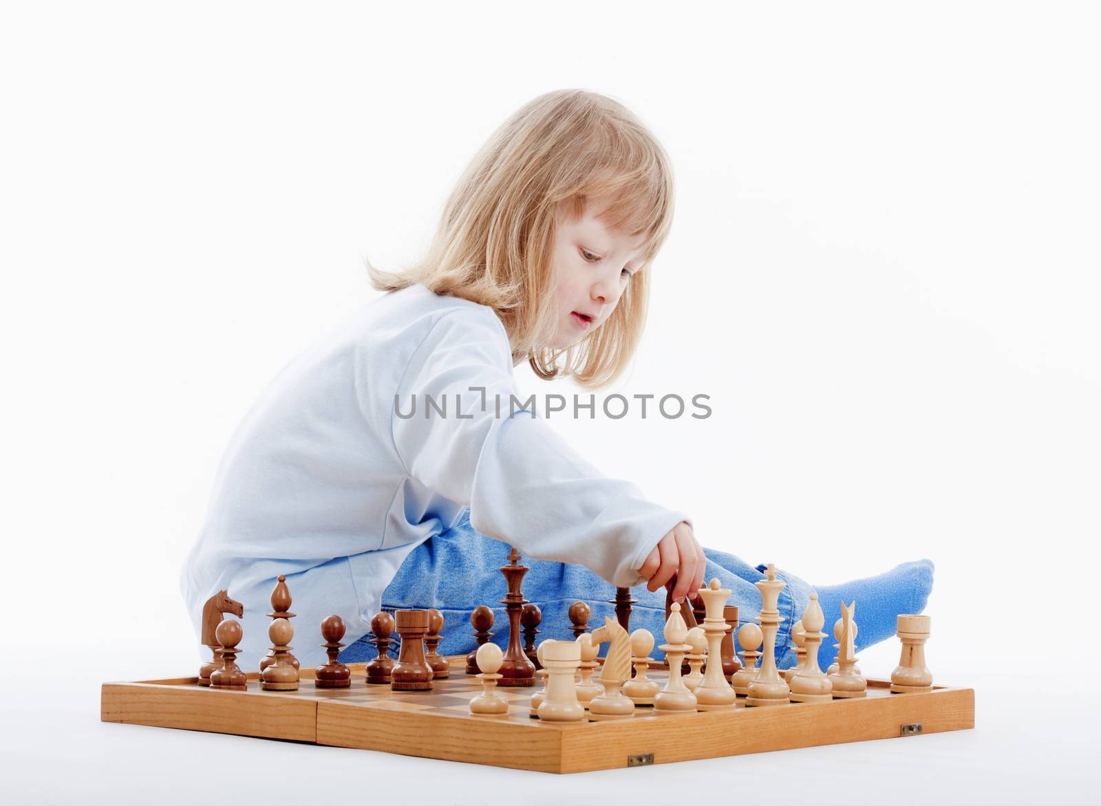 boy with long blond hair playing with chess pieces - isolated on white