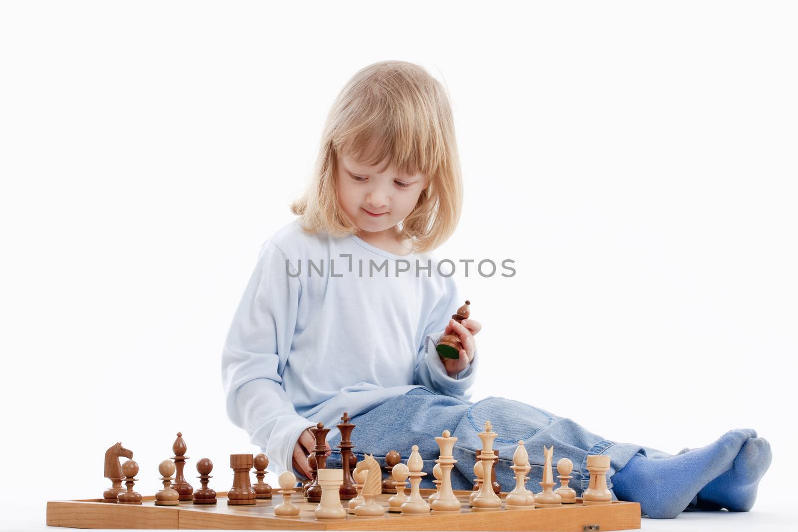 boy with long blond hair playing with chess pieces - isolated on white