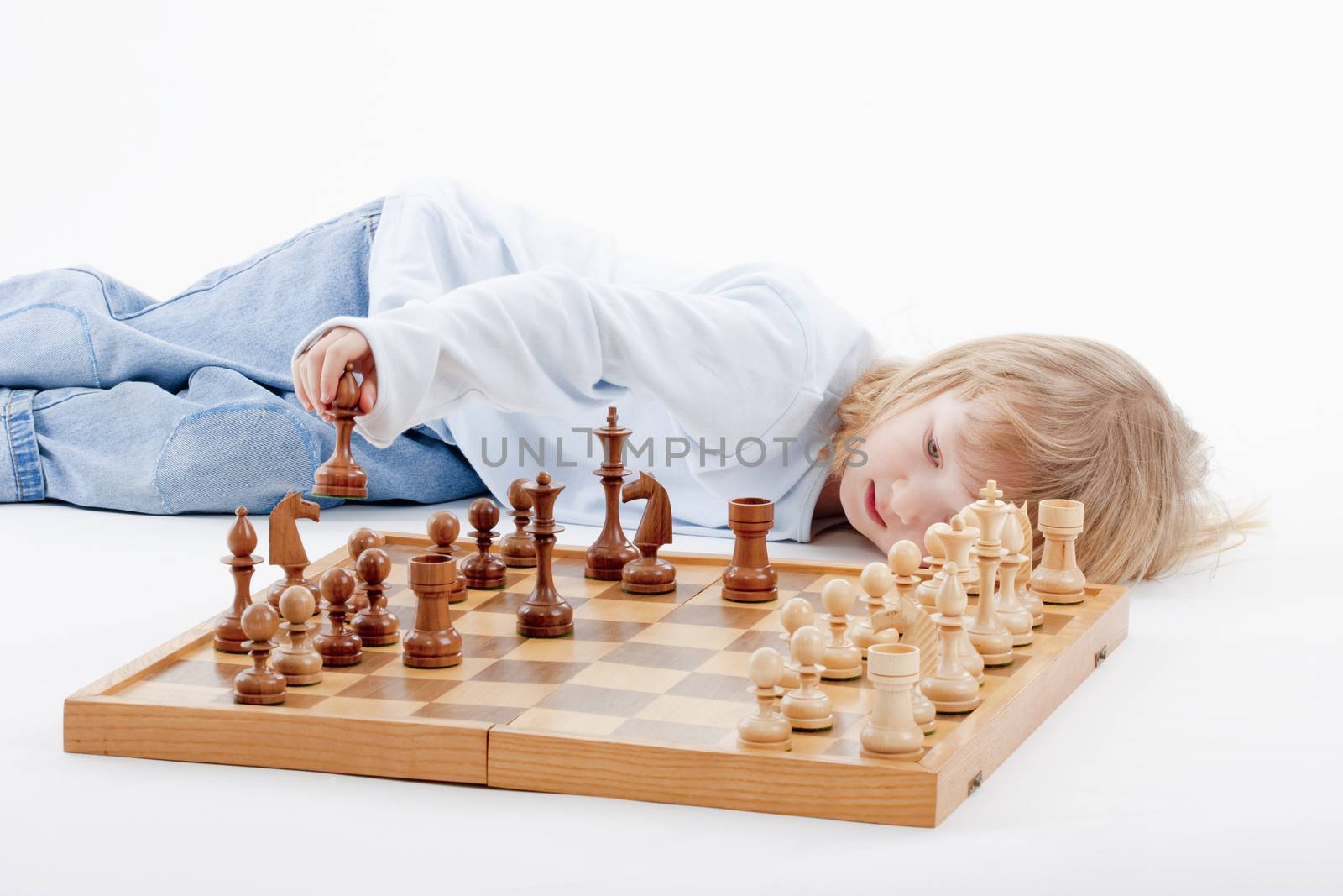 boy with long blond hair playing with chess pieces - isolated on white