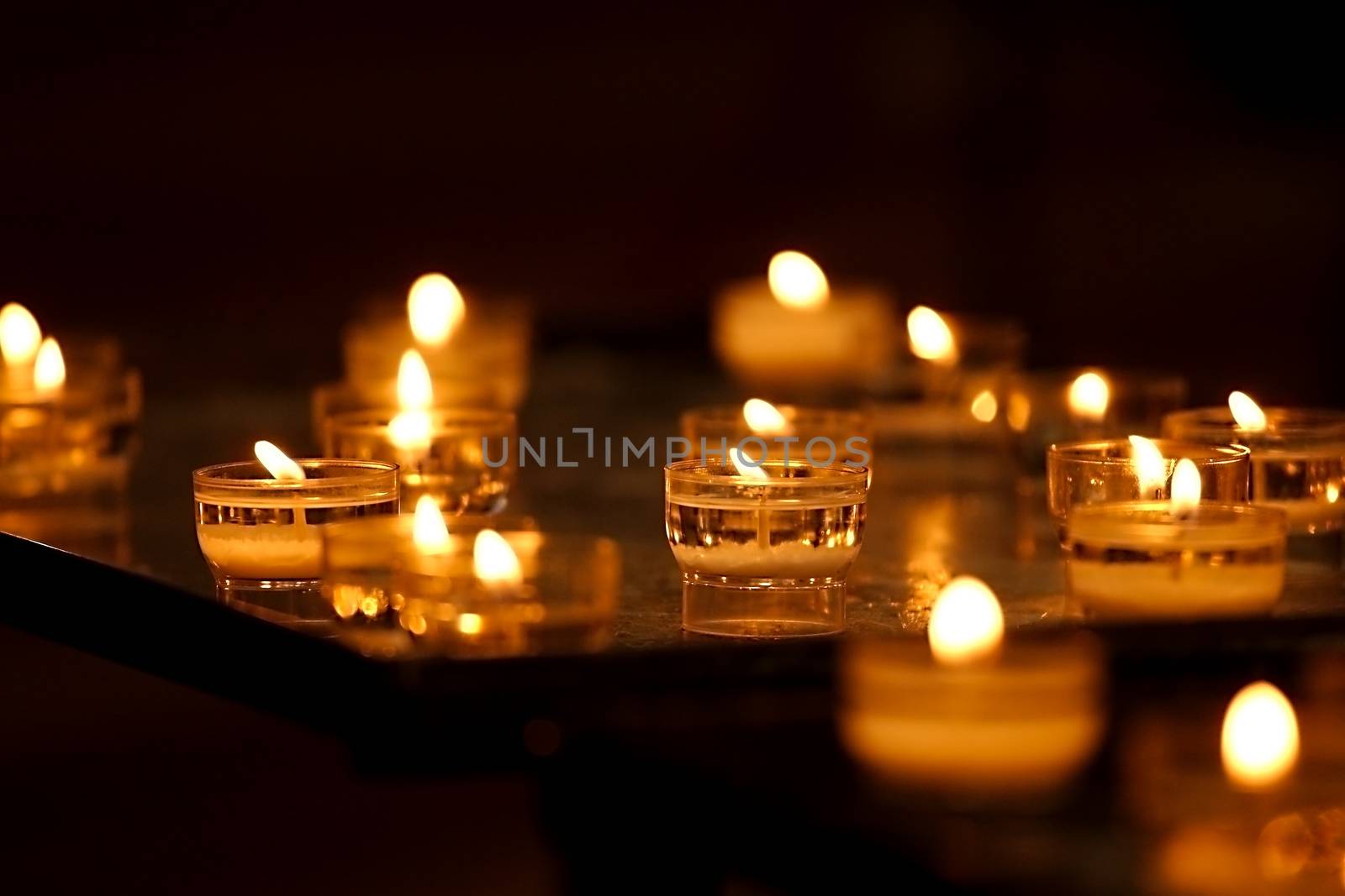 Rows of burning candles in a dim church