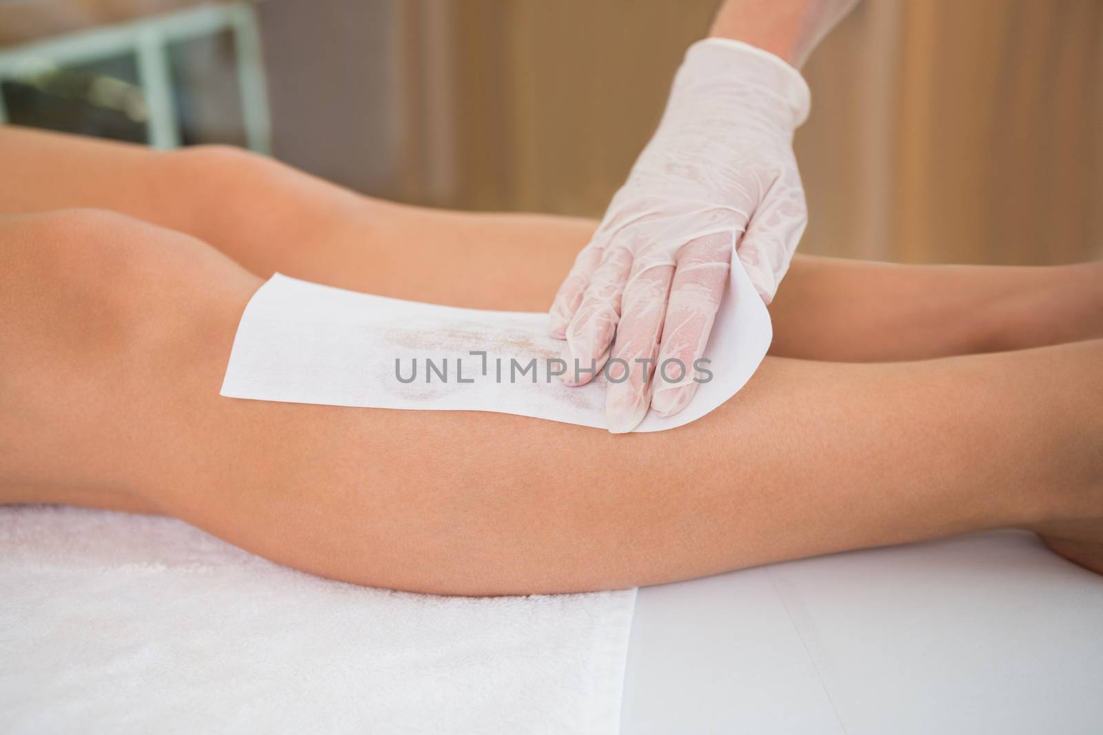 Woman getting her legs waxed by beauty therapist in the health spa