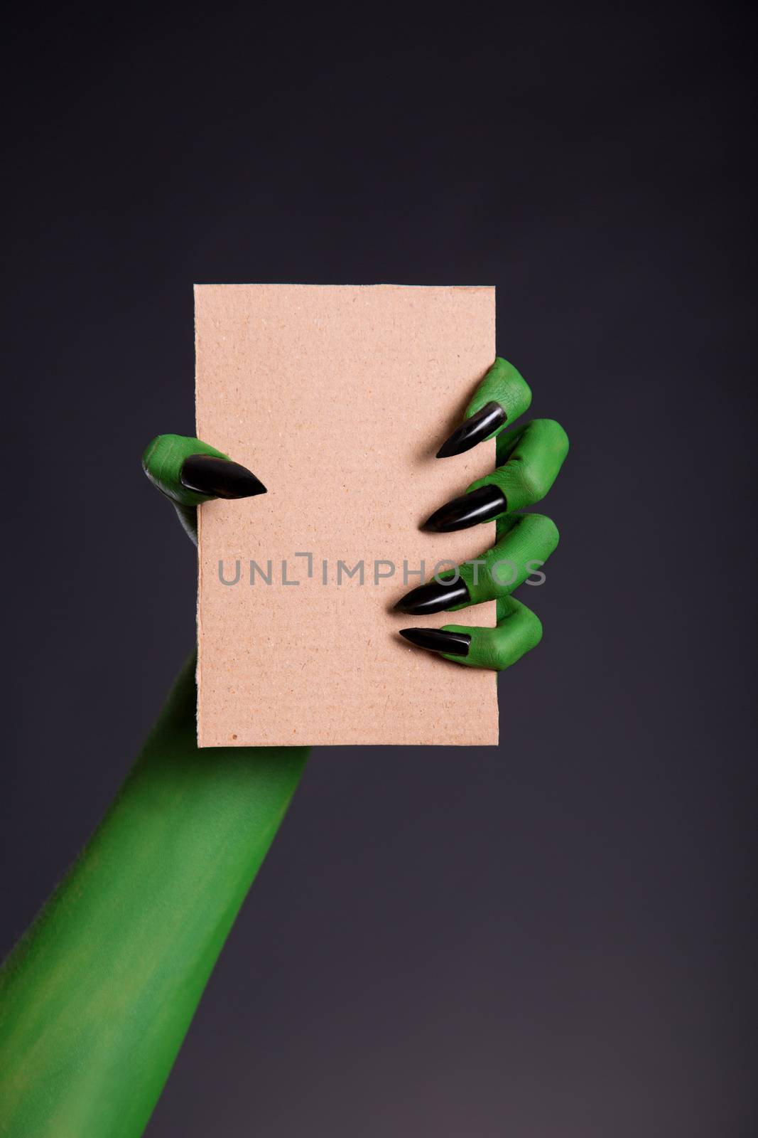 Green monster hand with black nails holding blank piece of cardb by Elisanth