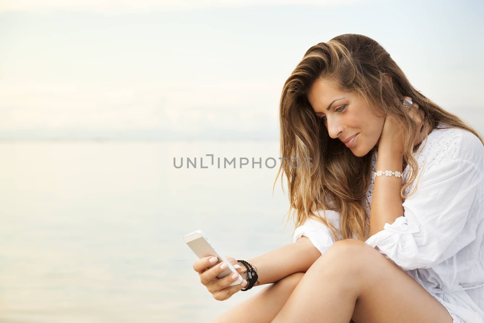 Smiling beautiful young woman using a mobile phone  by alessandroguerriero