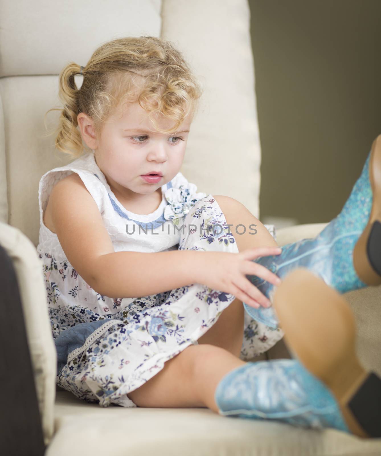 Adorable Blonde Haired Blue Eyed Little Girl Putting on Cowboy Boots.
