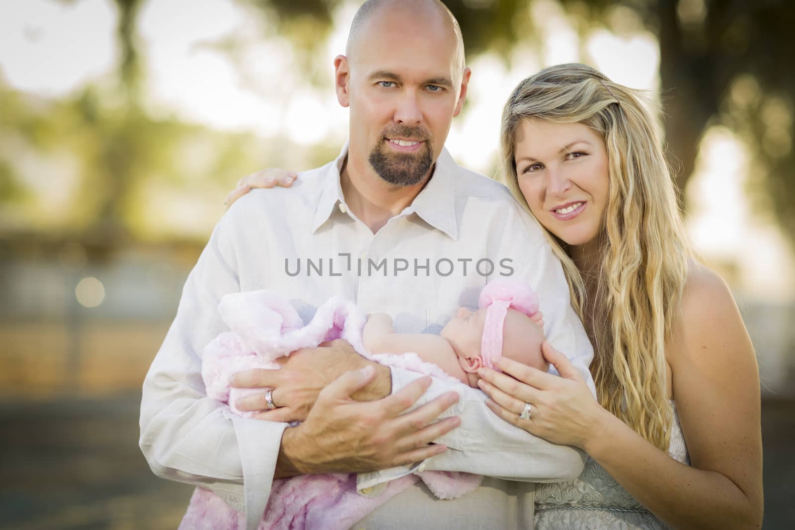 Beautiful Young Couple Holding Their Newborn Baby Girl Outside.