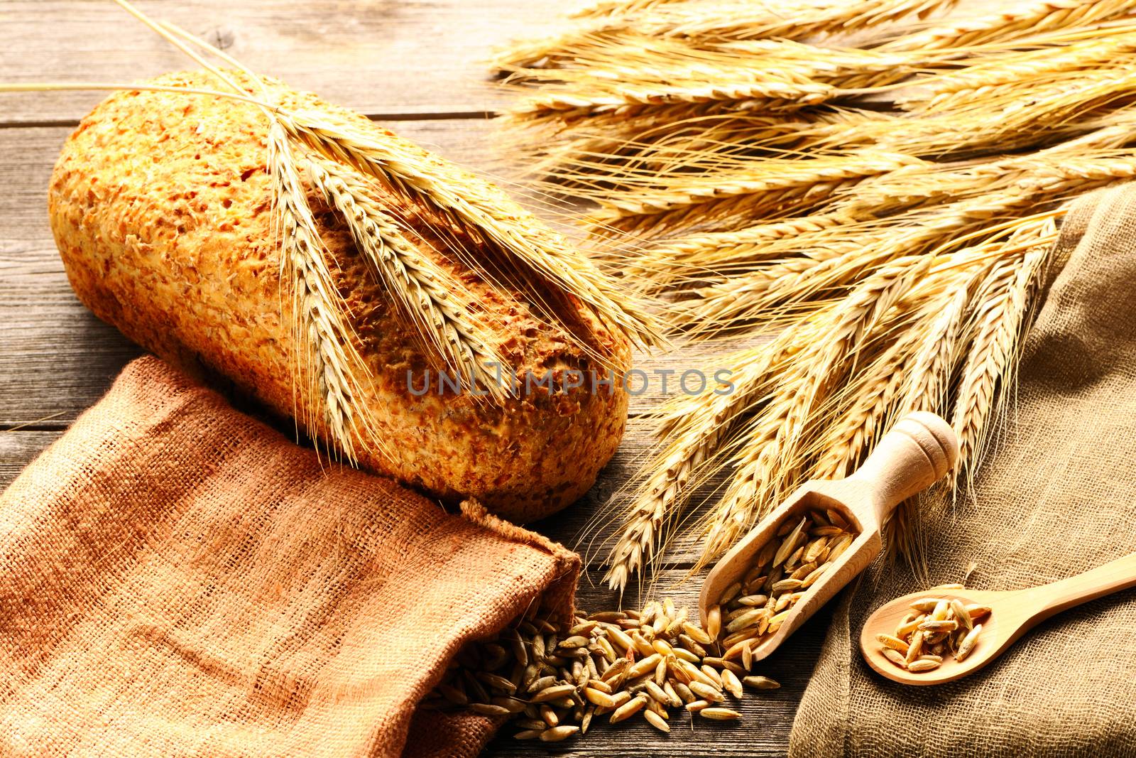 Rye spikelets and bread still life on wooden background by haveseen