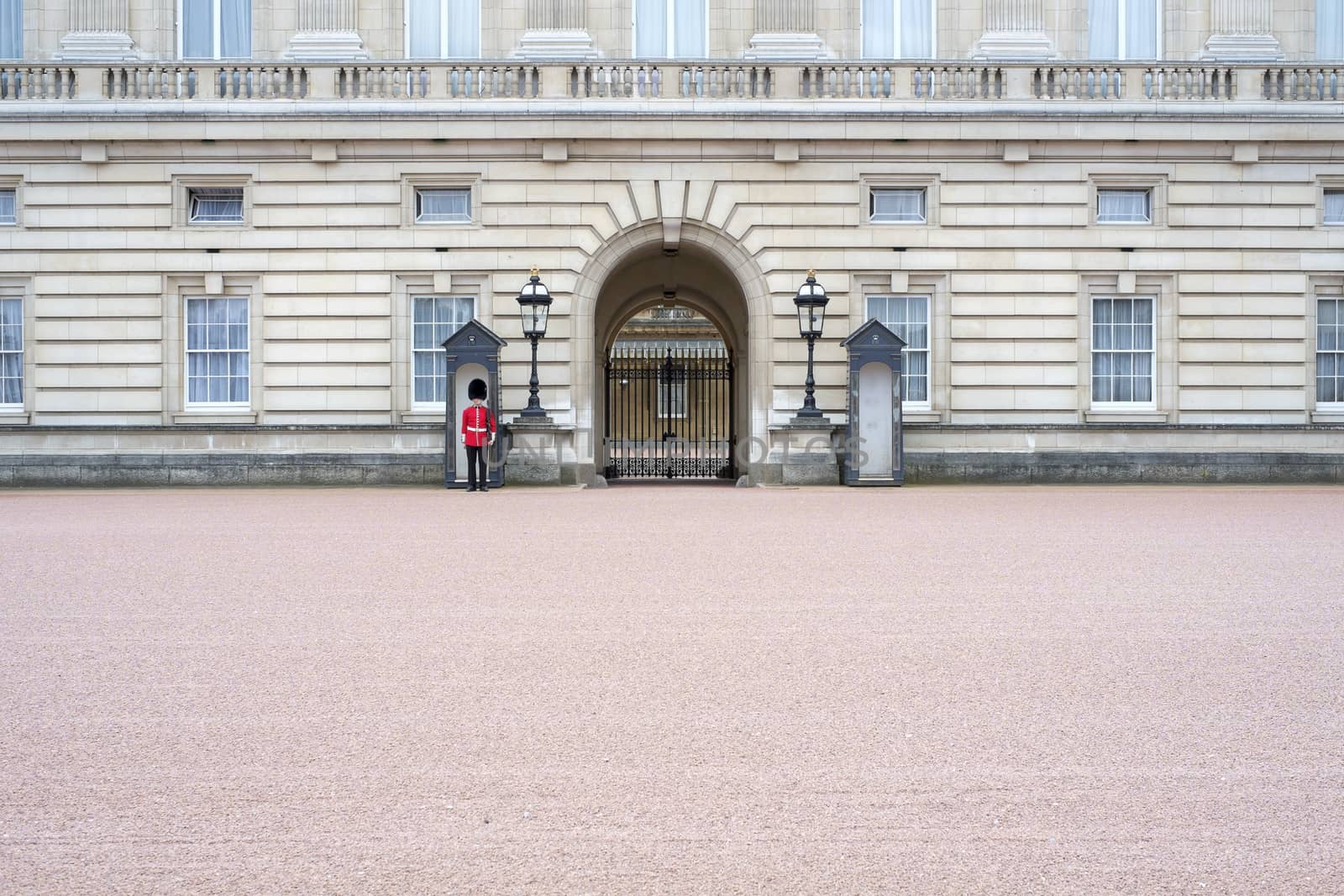 A lonely Queen's guard standing in front of Buckingham Palace gates in London, UK
