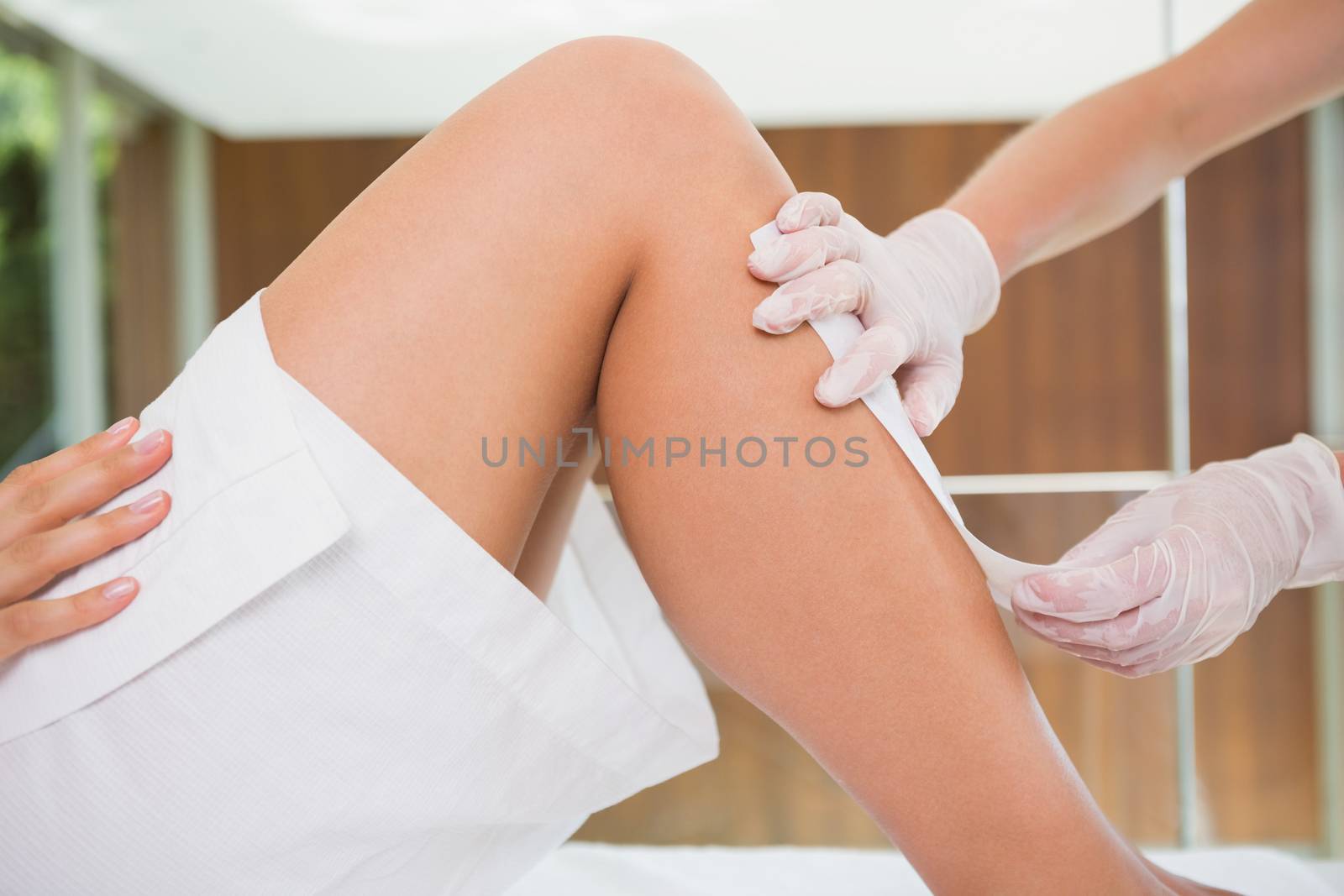 Woman getting her legs waxed by beauty therapist in the health spa