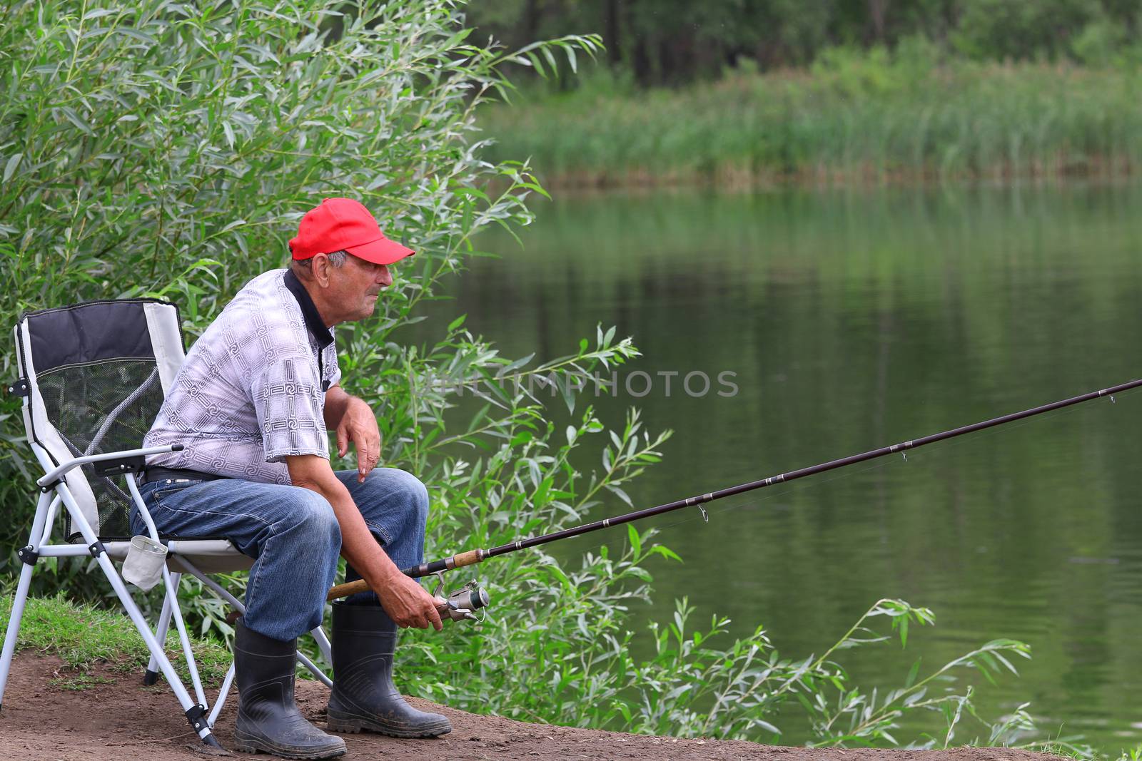 Fisherman fishes in the river. Middle aged man.