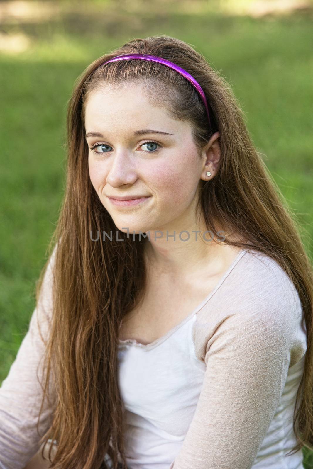 Grinning young female teenager sitting outside