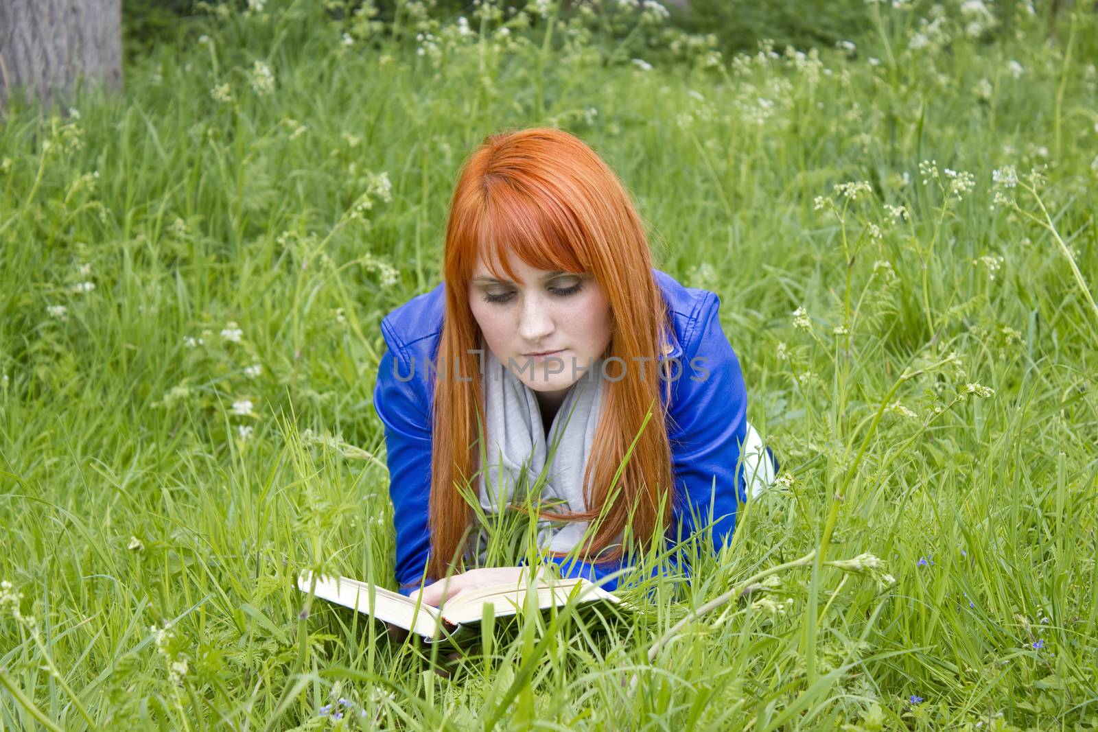 Young woman with red hair reading a book  by miradrozdowski