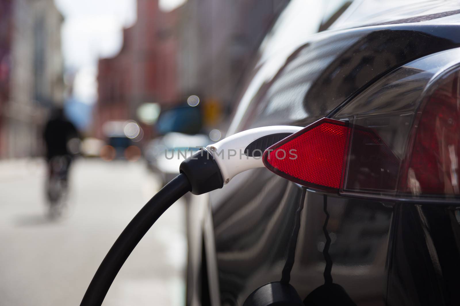 Power supply for electric car charging.  Electric car charging station. Close up of the power supply plugged into an electric car being charged.