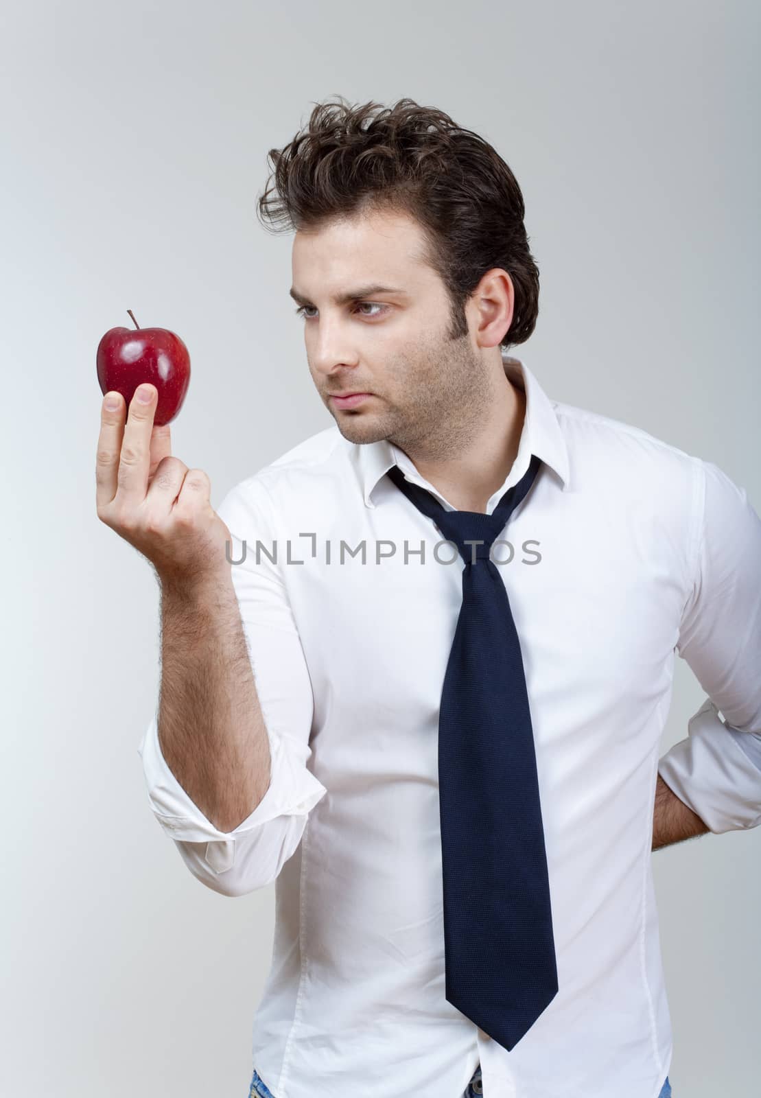 man in white shirt and tie holding red apple looking - isolated on gray