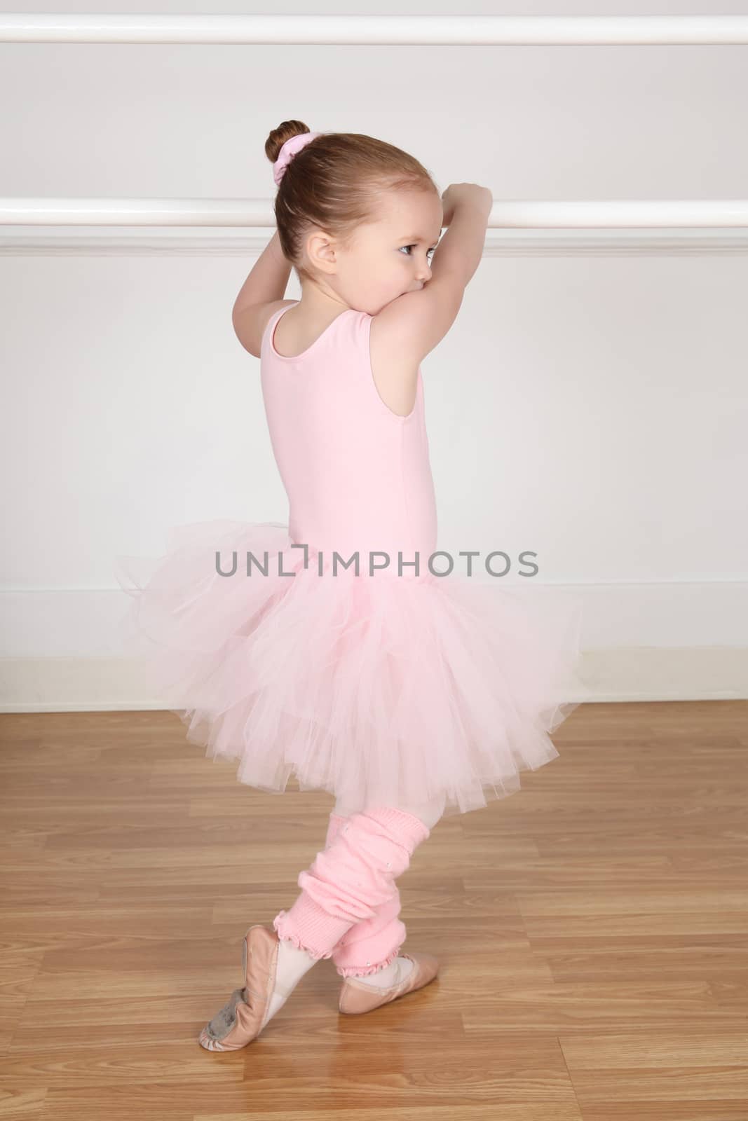 Beautiful little ballet dancer at the dance studio barre