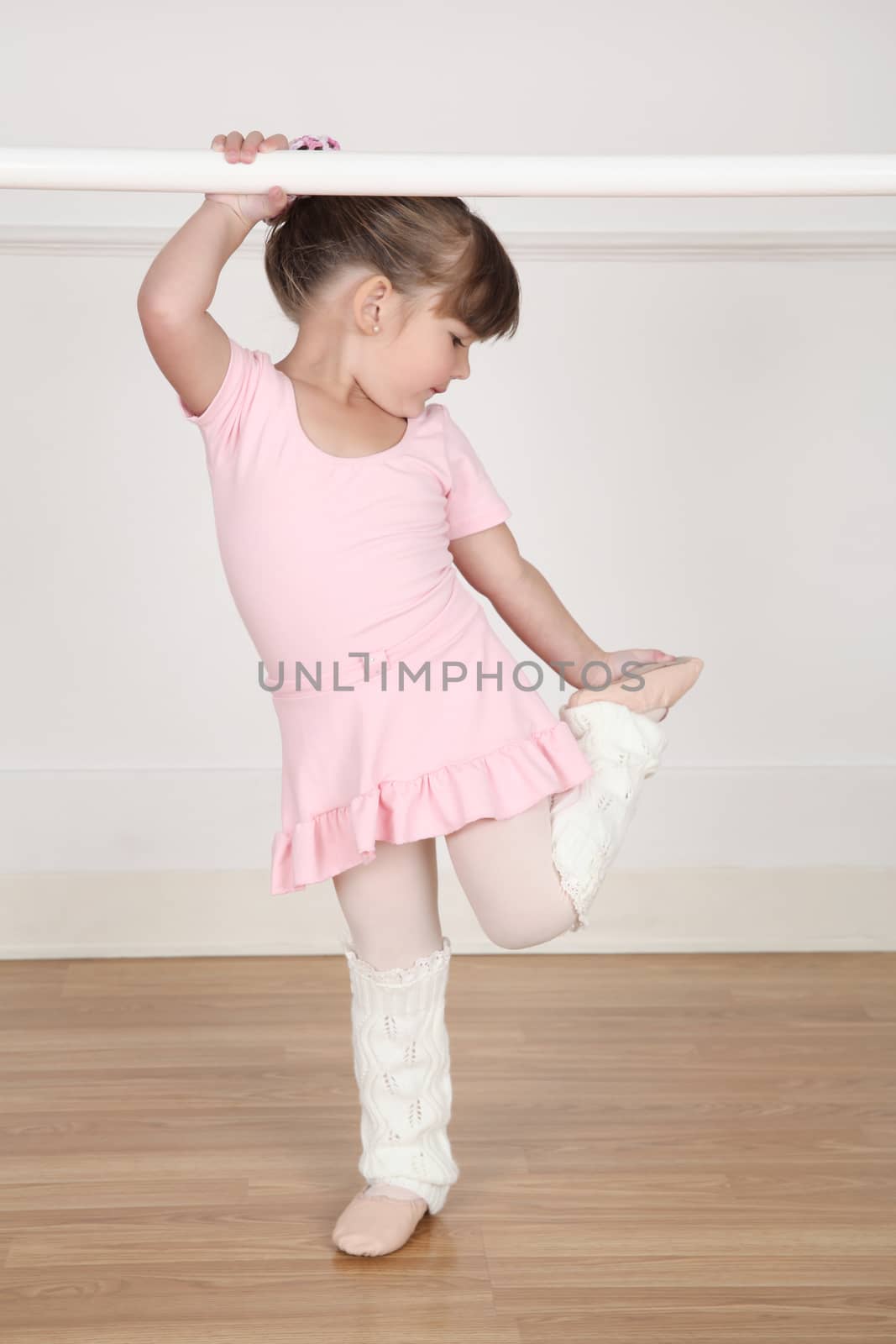 Beautiful little ballet dancer at the dance studio barre