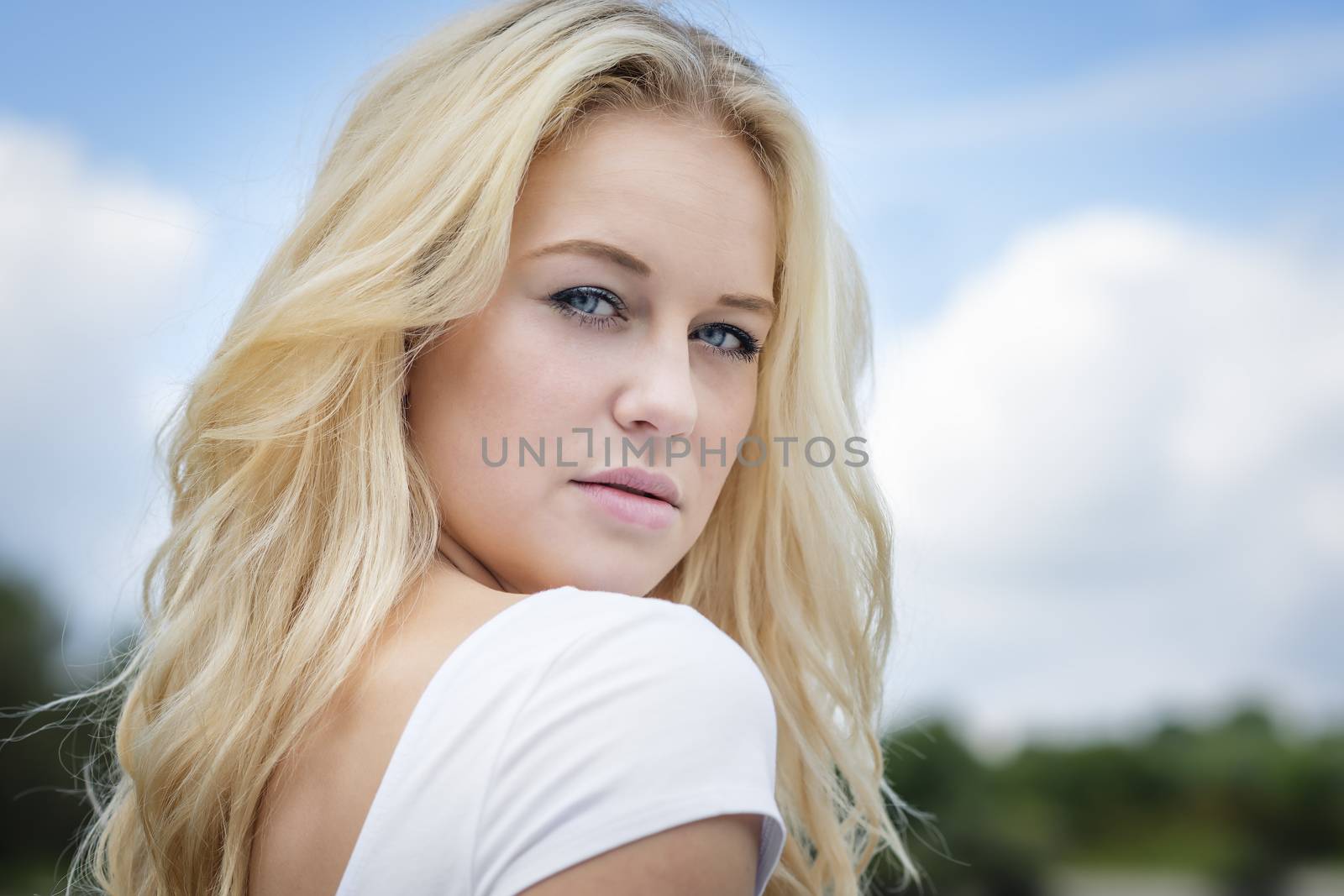 Outdoor portrait of a young blond woman in summer with blue sky