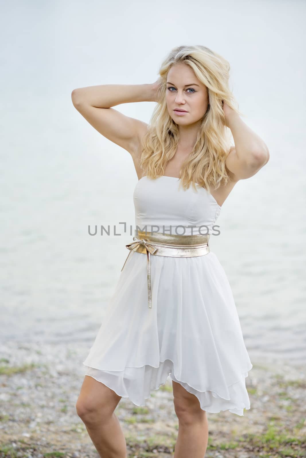Blond young woman standing on the edge of a lake