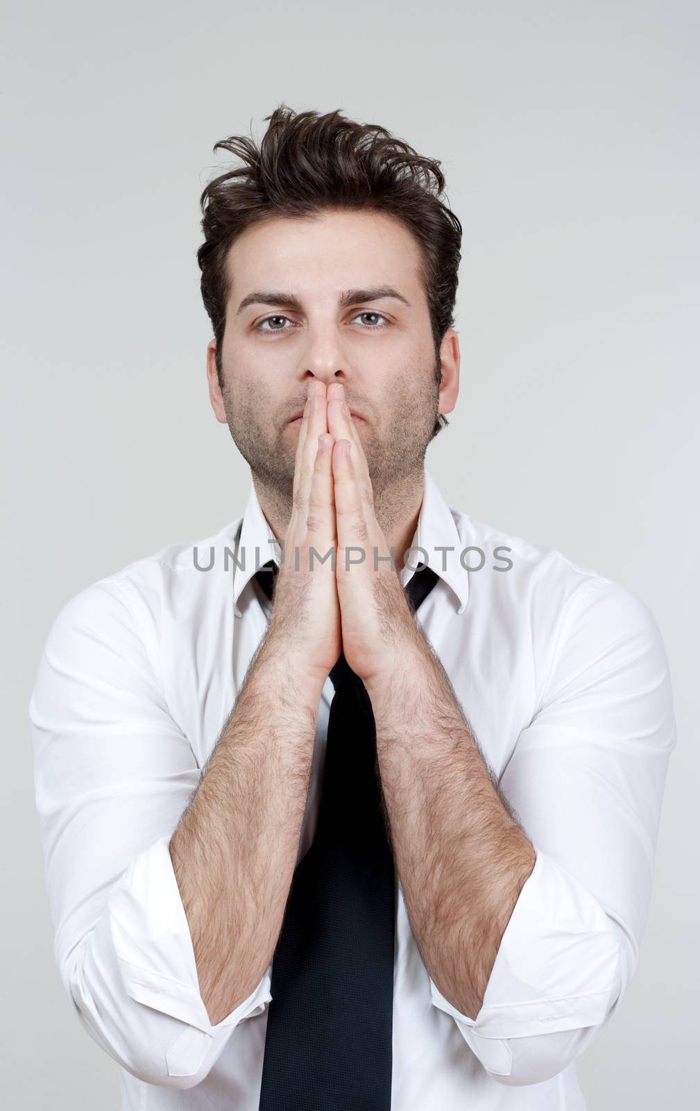 businessman in white shirt and tie holding hands together, praying - isolated on gray