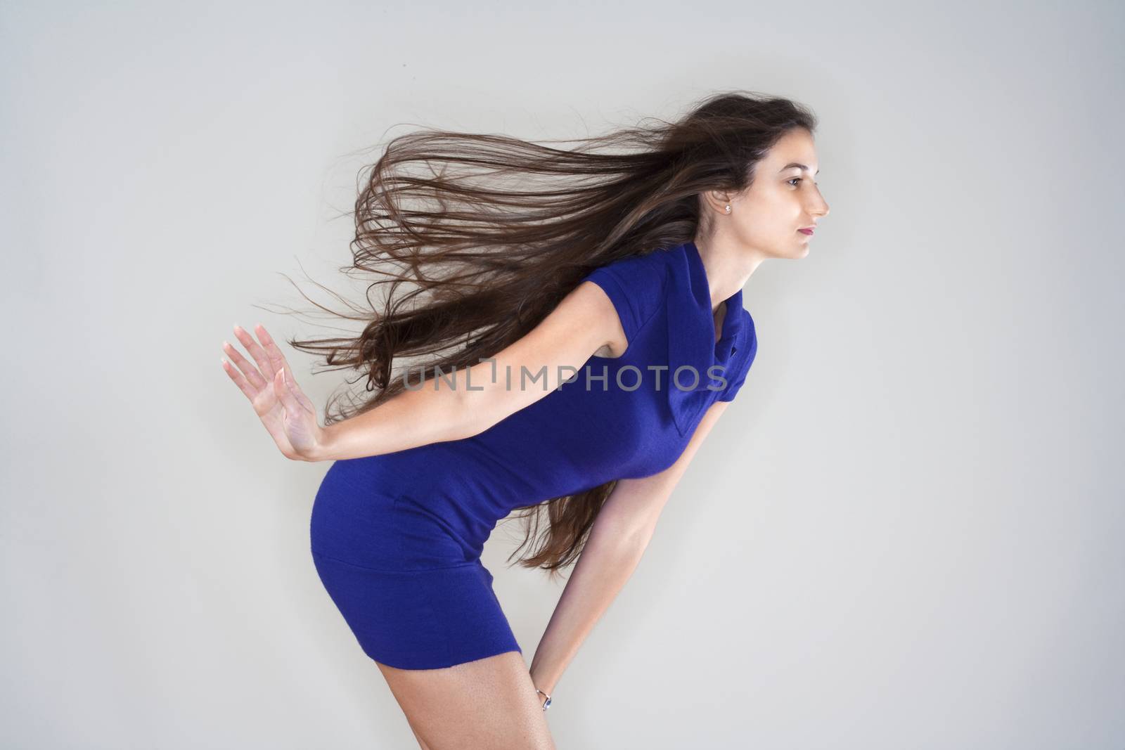 beautiful woman in blue dress with long brown hair flying - isolated on gray