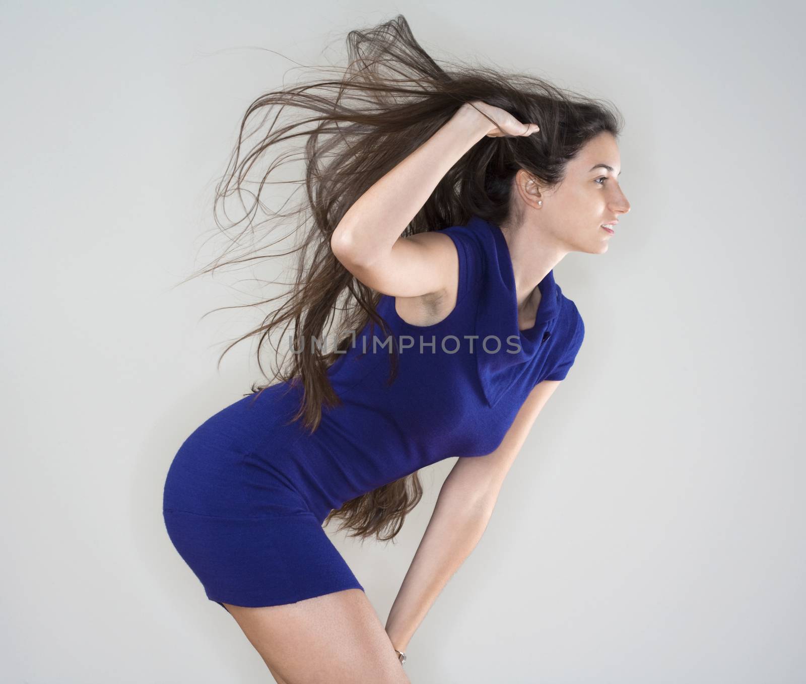 beautiful woman in blue dress with long brown hair flying - isolated on gray