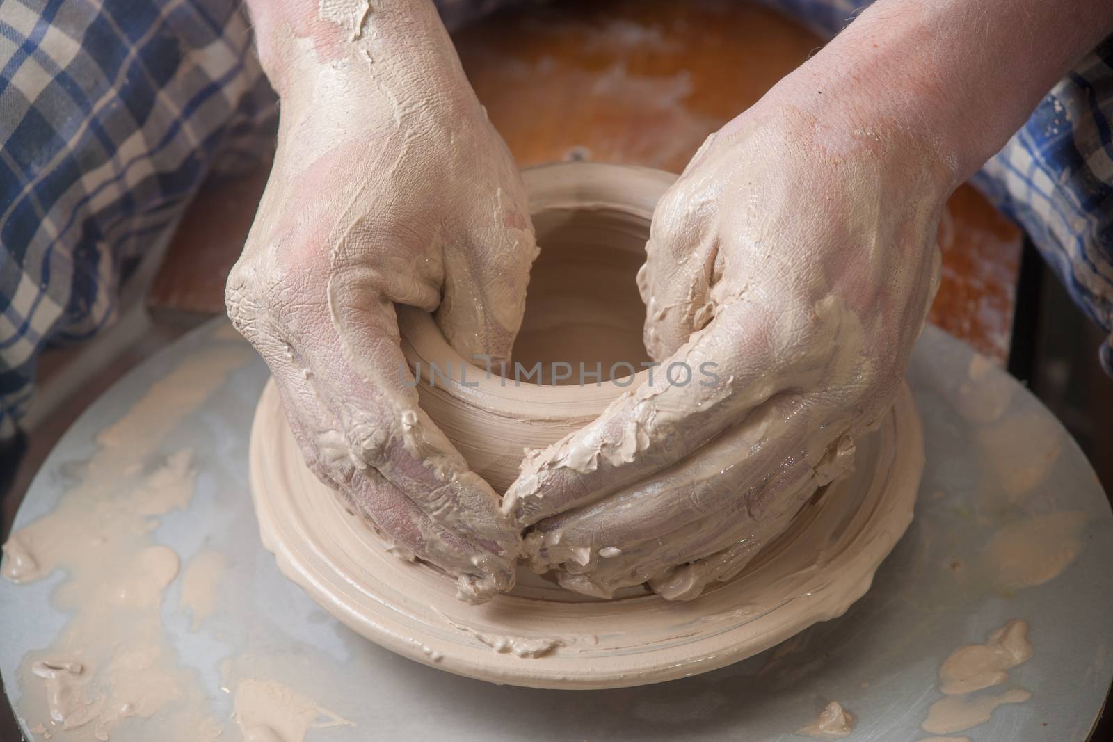 Hands of a potter, creating an earthen jar on the circle