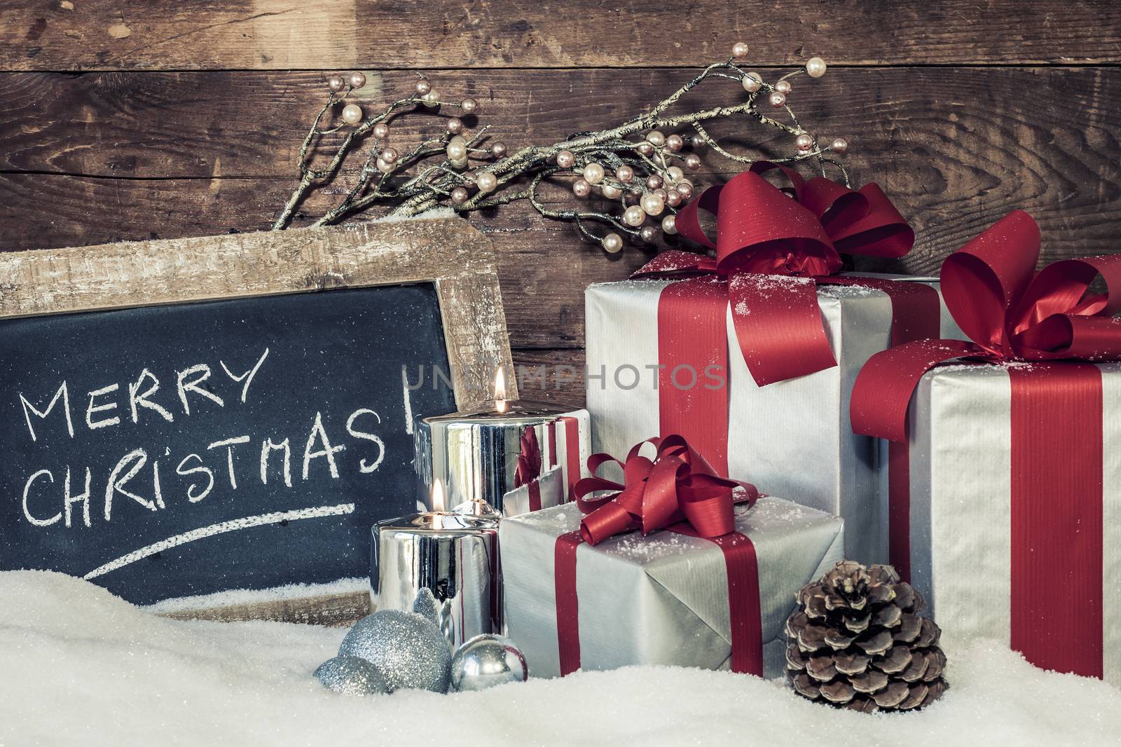 Closeup of Christmas gifts with candles and slate.