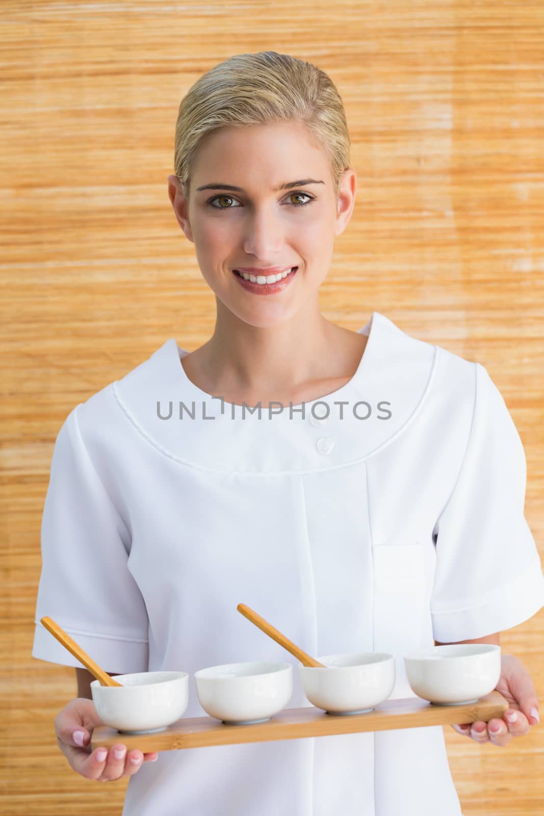 Smiling beauty therapist holding tray of treatments by Wavebreakmedia