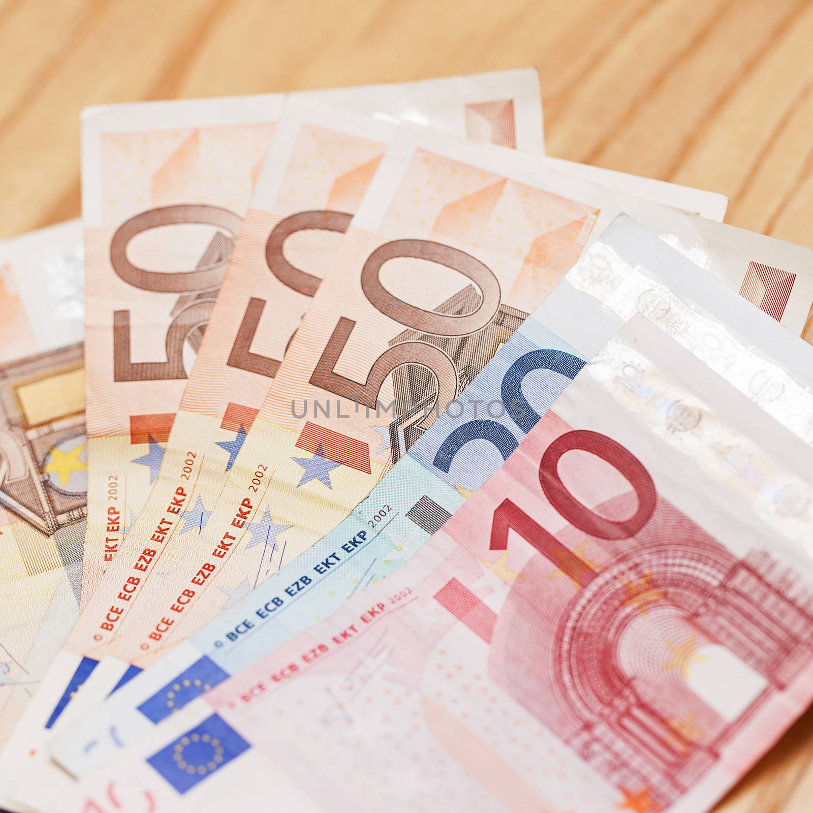 Heap of different euro banknotes on a wooden table