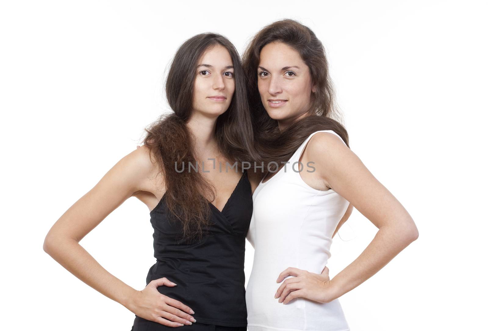 two sisters with long brown hair holding each other, looking