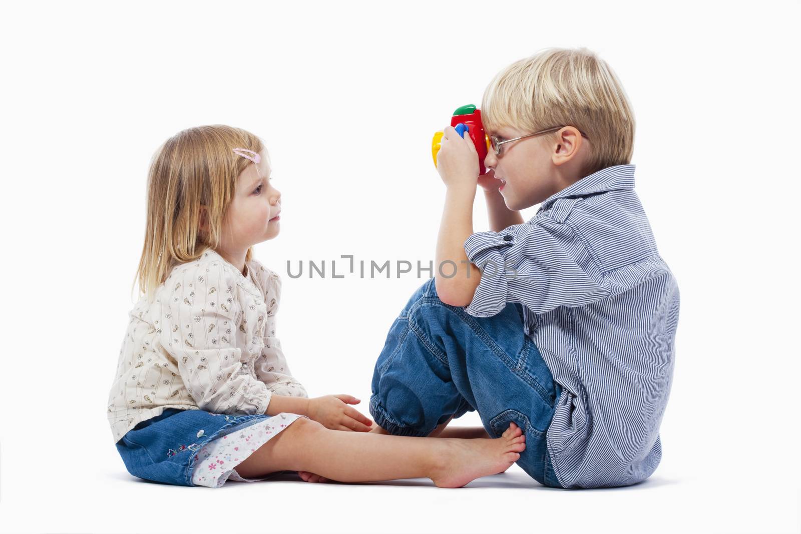 siblings taking pictures of each other with toy camera - isolated on white