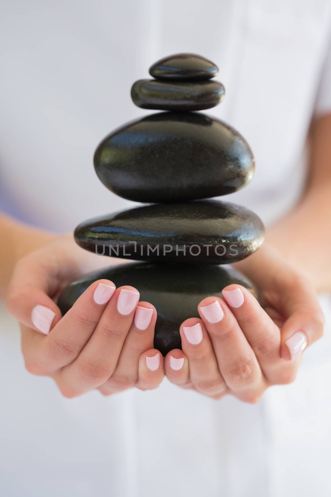 Beauty therapist holding pile of stones for massage by Wavebreakmedia