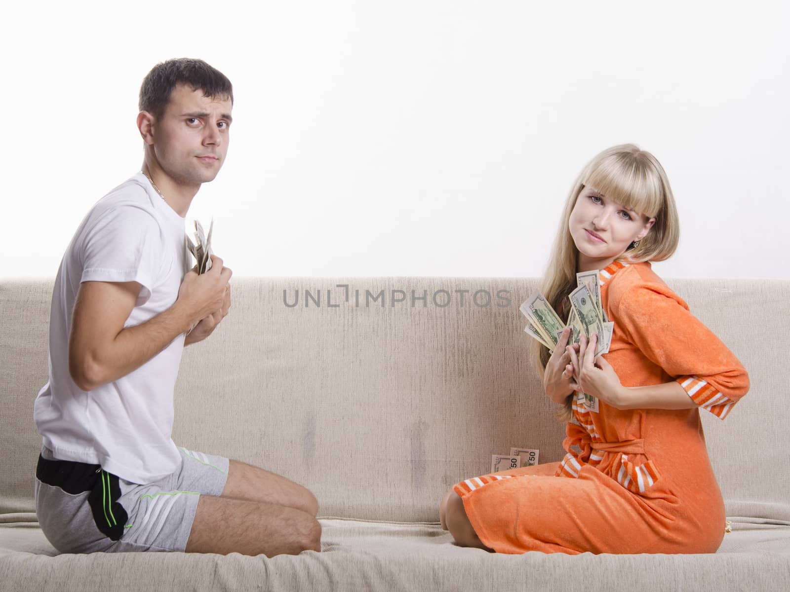 Young couple sitting on the couch, facing each other. They divided salary, each bale presses his part to himself