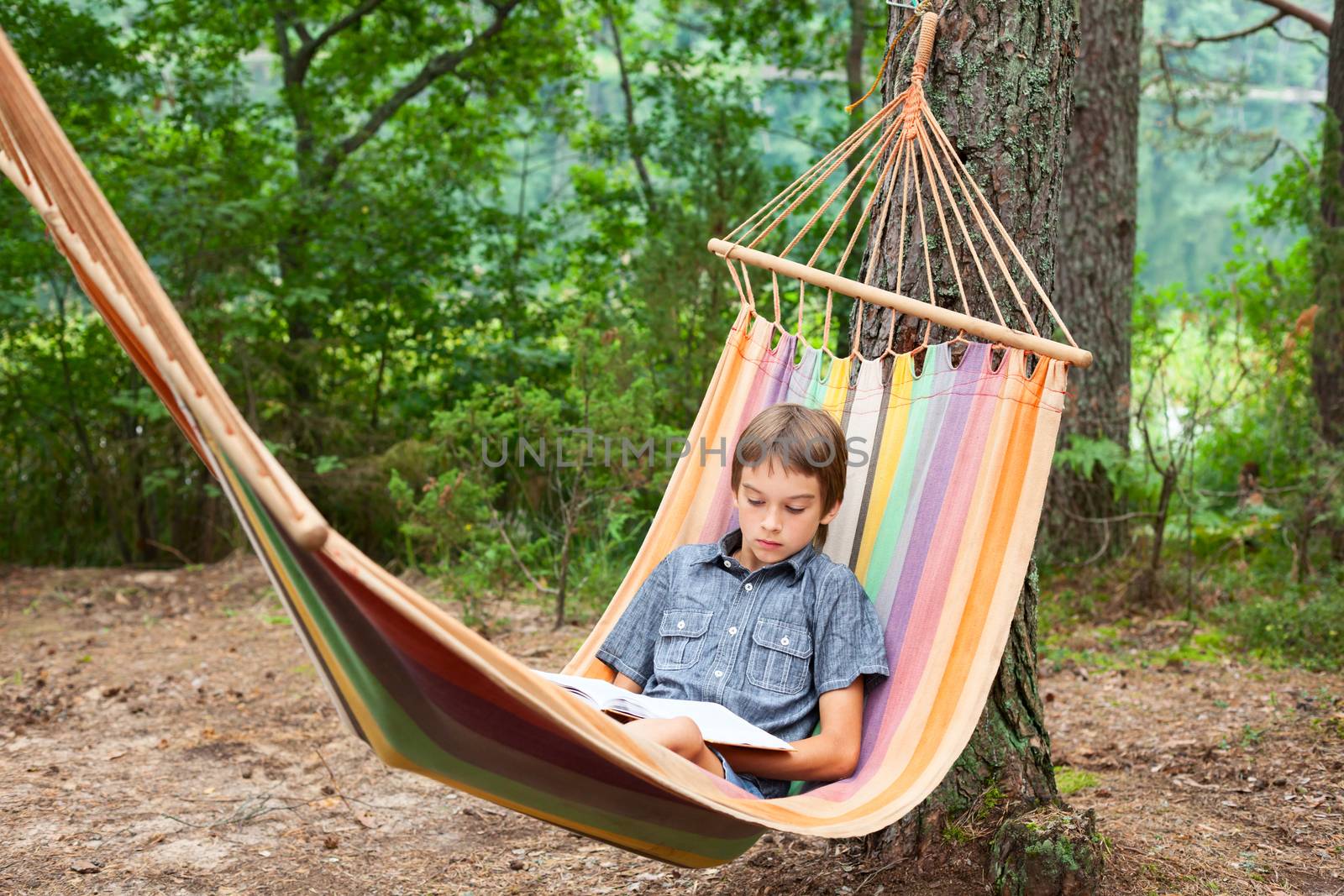 Child reading book in hammock by naumoid