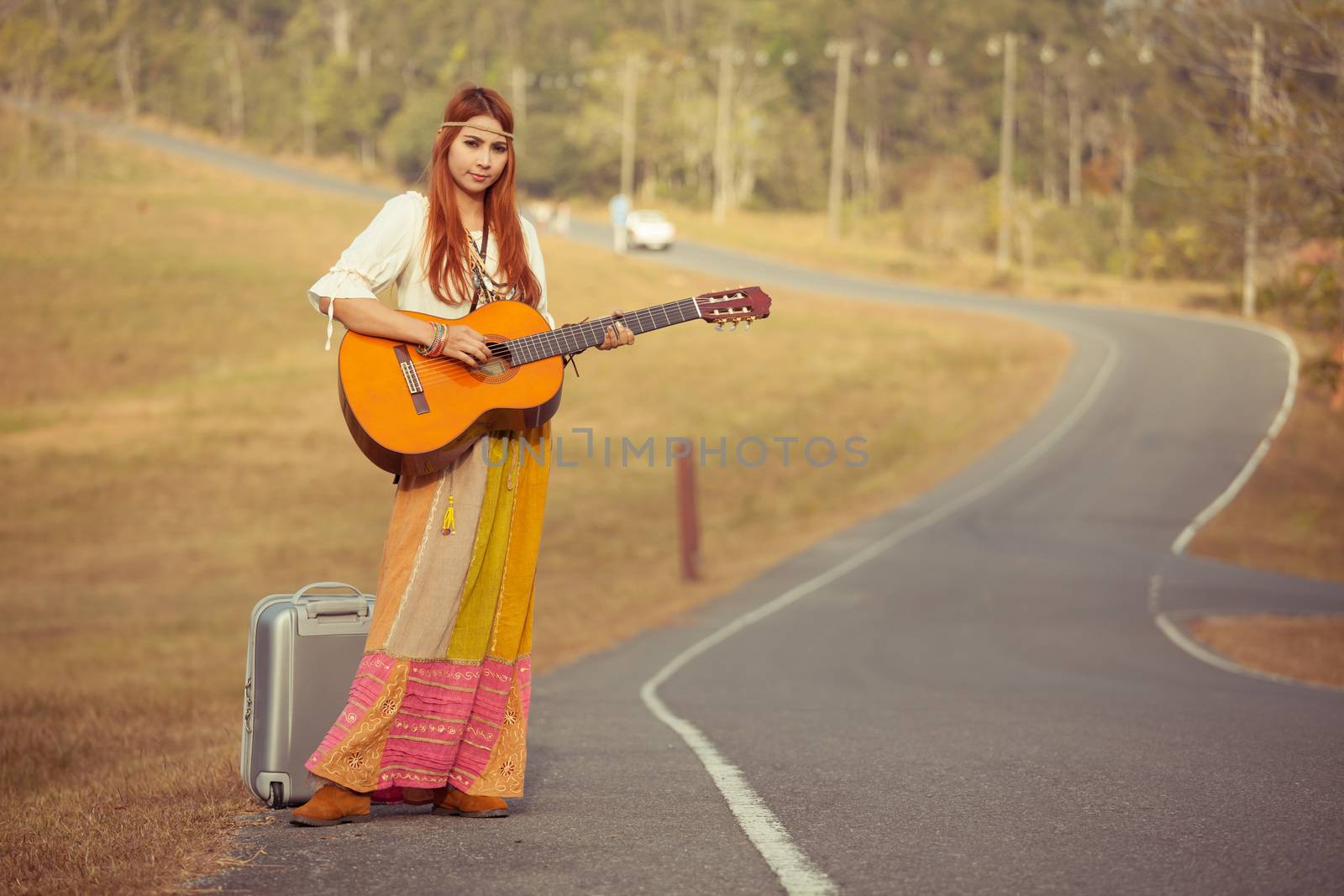 Hippie woman playing music and dancing on the country road