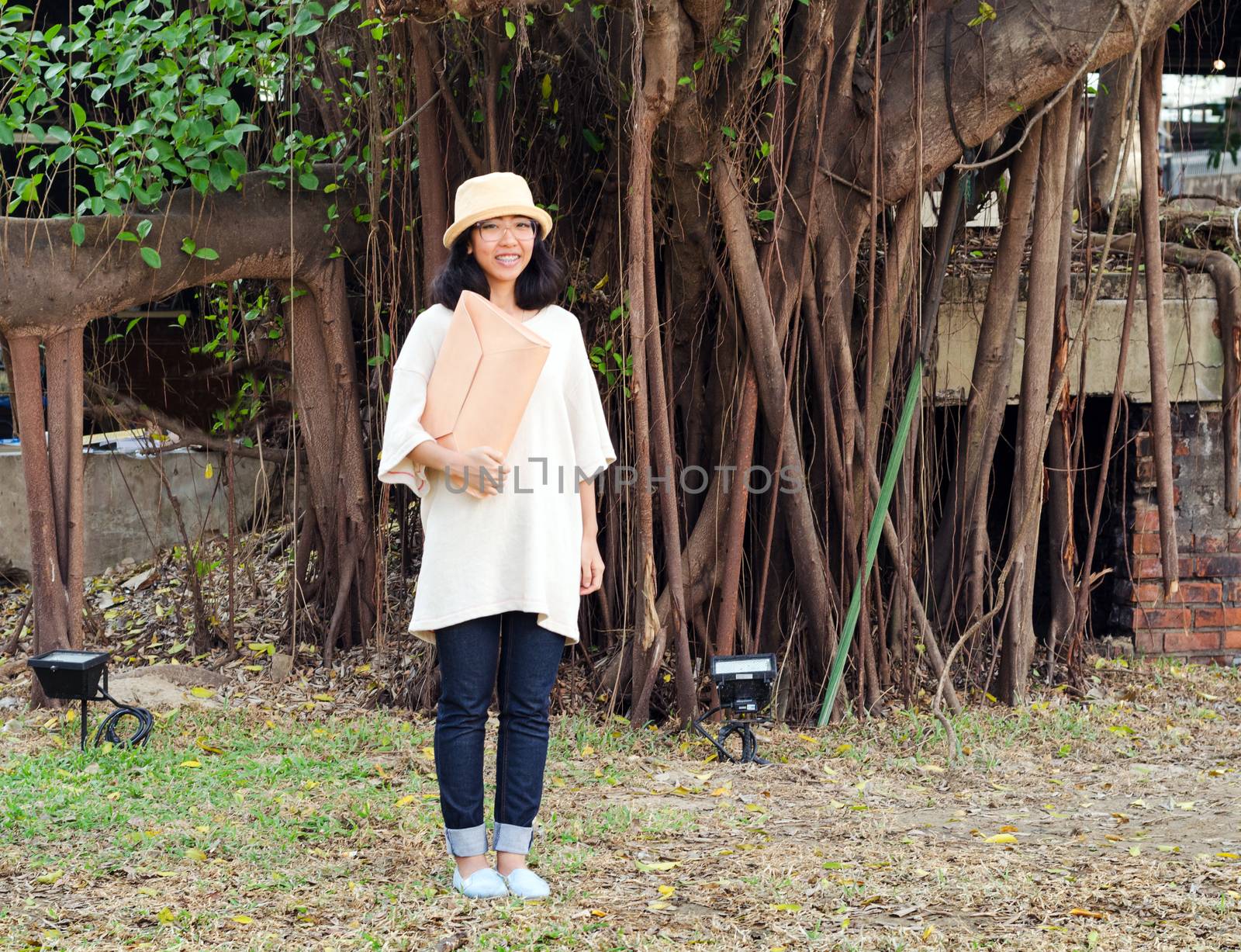 Young fashion girl with handbag on banyan tree background