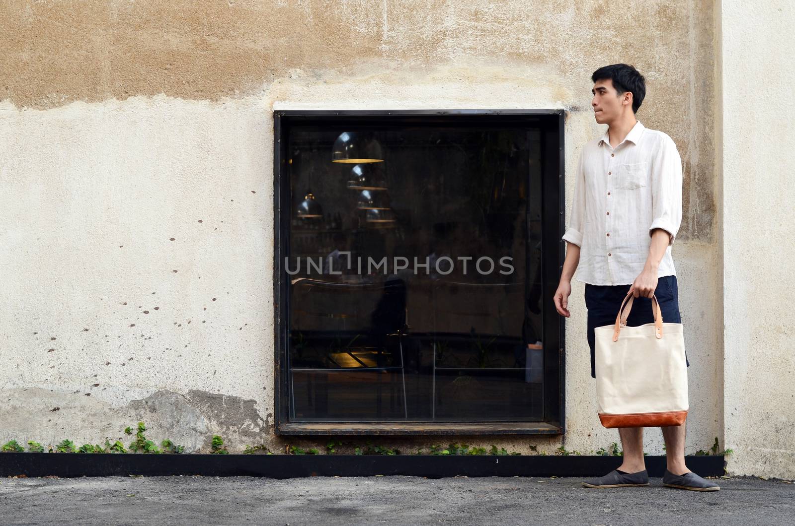 Asian man with canvas bag on grunge concrete background