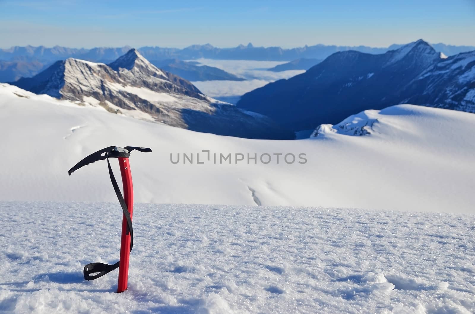 Ice ax stuck in the snow high in the mountains above the glacier