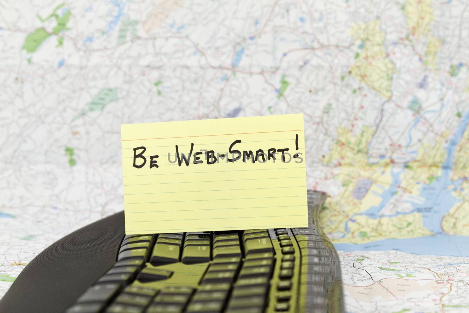 Be Web-Smart note written on yellow note card placed on black keyboard.  Map background.  Focus on technology warning phrase for Internet users.  Depicts need for smart tech behavior to be secure and avoid worldwide threats of virus and hacking.  Wise warning for personal computing, business, banking, government, schools, and any agency connected to today's technology. 