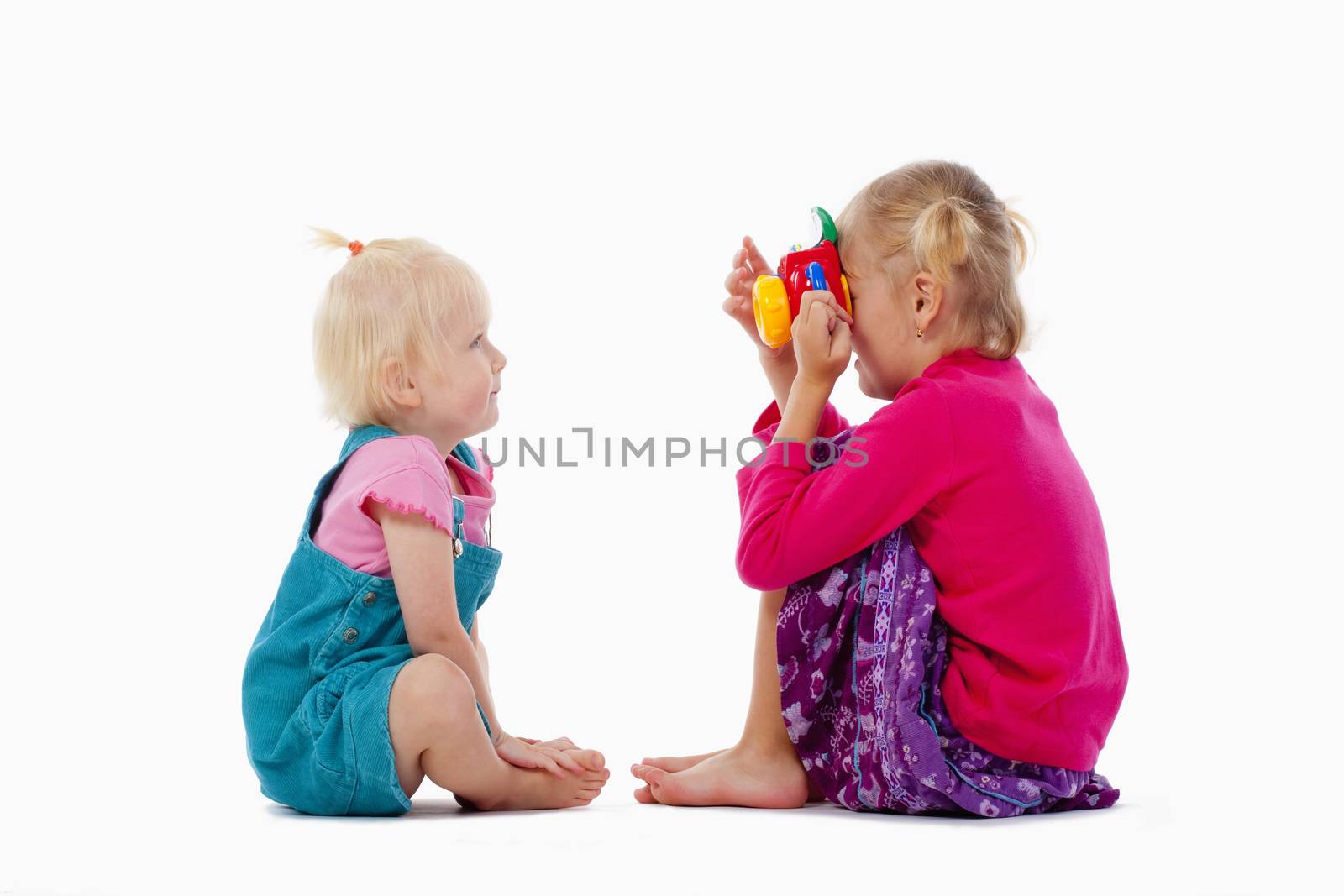 sisters taking pictures of each other with toy camera - isolated on white