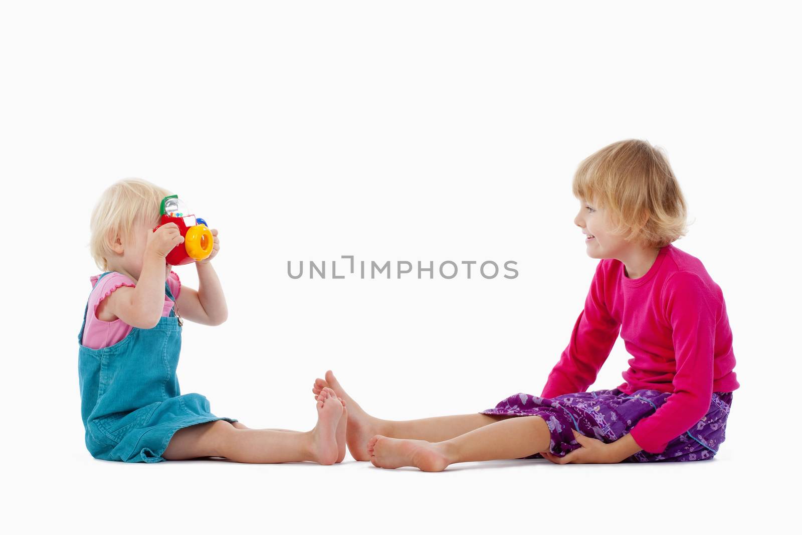 sisters taking pictures of each other with toy camera - isolated on white