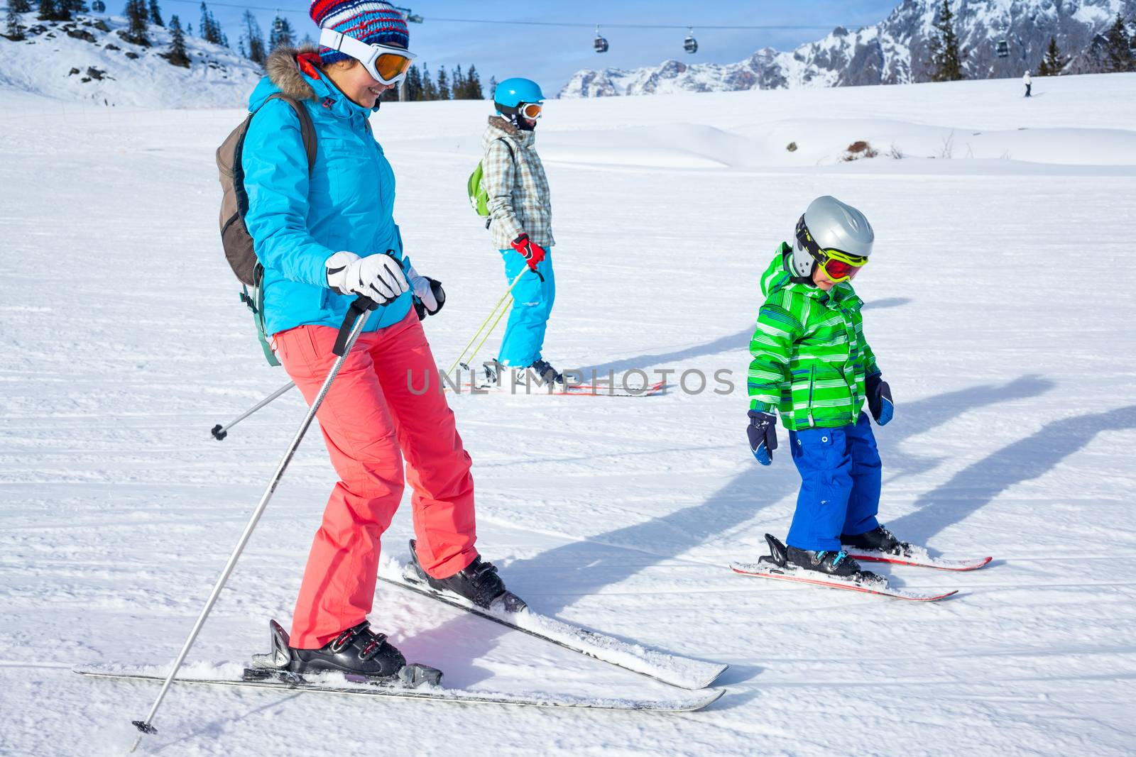 Ski, winter, snow, skiers, sun and fun - Mother with two happy kids enjoying winter vacations.